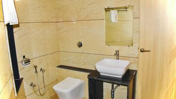 A bathroom with a white toilet, a sink, a mirror, and a shower area.