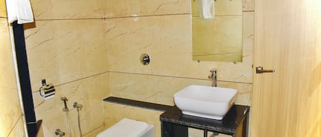 A bathroom with a white toilet, a sink, a mirror, and a shower area.