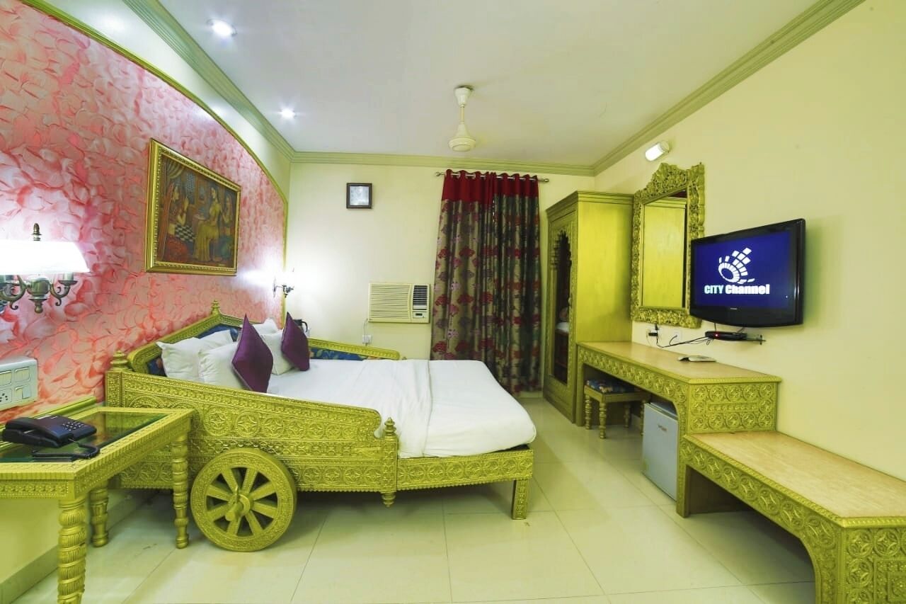 A hotel room with a bed, a television, a desk, and a chair.