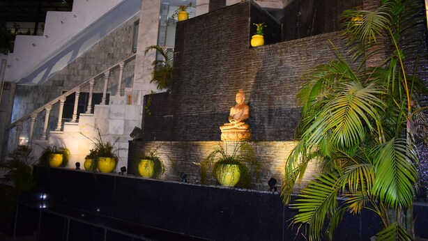 A staircase with a Buddha statue, potted plants, and a modern architectural design.