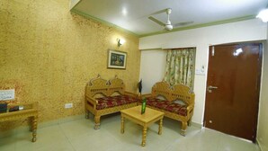A room with two ornate sofas, a small table, a ceiling fan, a door, and a wall-mounted light fixture.