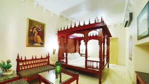 A traditional room with a four-poster bed, a sofa, and a glass coffee table.
