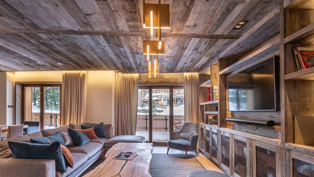 A modern living room with a wooden ceiling, a large sofa, a coffee table, and a television. - Luxurious 7-room apartment for 14 pers. in Avoriaz with wellness access (Avoriaz)