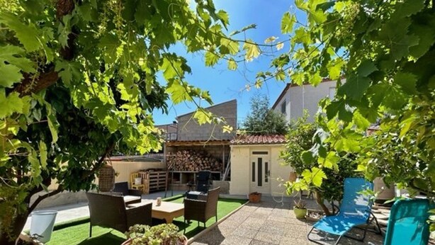 Eine Terrasse mit Gartenmöbeln, einem kleinen Tisch mit einer Pflanze und einem blauen Stuhl.