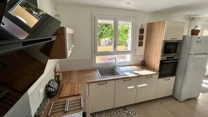 Eine moderne Küche mit Fenster, eingebautem Ofen und weißen Schränken.