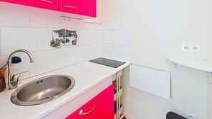 A kitchen with a sink, a countertop, and a small window with a floral design. - Ground Floor Apartment with Terrace, Near Shops, Sleeps 4 (Merville-Franceville-Plage)