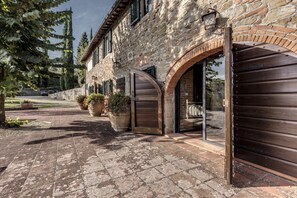 Un bâtiment en pierre doté de grandes portes en bois et d’une cour dallée.