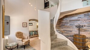 A modern interior with a curved staircase, a plush armchair, and a glass table. - Villa Benedetta - Homelike Villas (Osimo)