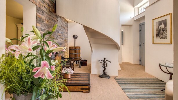 A spacious interior with a curved staircase, a wooden bench, and a variety of plants. - Villa Benedetta - Homelike Villas (Osimo)