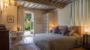 Un dormitorio con cama, mesita de noche, lámpara y vistas al exterior.