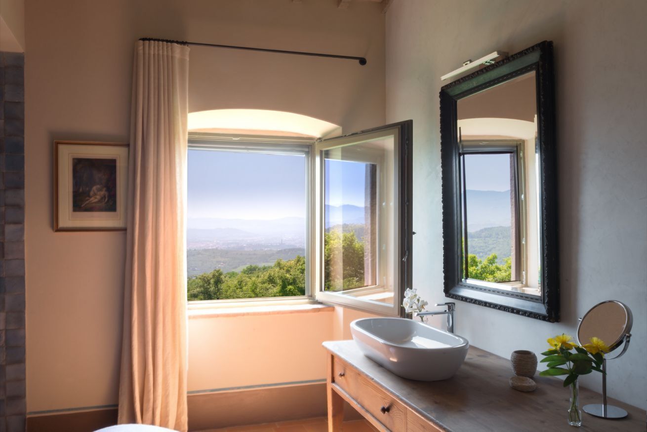 A bathroom with a large window, a sink, and a mirror.