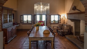 Un amplio comedor con una larga mesa de madera, rodeado de sillas, bajo un arco de ladrillo.