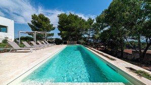 A rectangular swimming pool with clear blue water, surrounded by lounge chairs and a pergola. - Villa Calipso - Homelike Villas (Nardò)