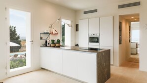 A modern kitchen with white cabinets, a marble countertop, and a built-in oven. - Villa Calipso - Homelike Villas (Nardò)