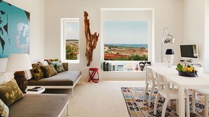 A modern living room with a large window, a sofa, a dining table, and a bookshelf. - Villa Calipso - Homelike Villas (Nardò)