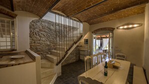 A rustic interior with a stone wall, wooden staircase, and a dining area with a table and chairs. - Villa Chianti - Homelike Villas (Terranuova Bracciolini)