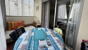 A cozy room with a bed, a window with blinds, a sliding glass door, and a view of the outside. - Cozy Studio for 2 Near Beach with Private Parking (Cap d'Agde)