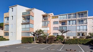 A multi-story residential building with balconies, a parking lot, and well-maintained landscaping. - Cozy Studio for 2 Near Beach with Private Parking (Cap d'Agde)
