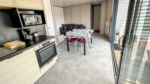 Eine kompakte Küche mit modernen Geräten, ein Essbereich mit Tisch und Stühlen sowie eine Sitzecke mit einer Couch.