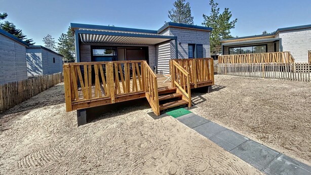 Eine moderne, wohnmobilähnliche Unterkunft mit einer Holzterrasse und einem überdachten Außenbereich.