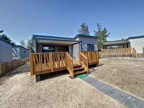 Un alloggio moderno in stile camper con terrazza in legno e area esterna coperta.