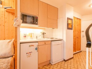 A compact kitchen with wooden cabinets, a microwave, a dishwasher, and a sink. - Duplex in Avoriaz, 2 bedrooms, 6 people, 50m² (Avoriaz)