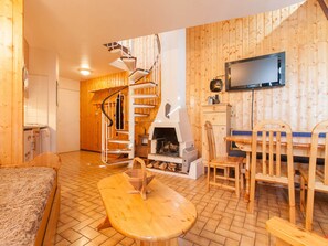 A cozy cabin interior with a wooden interior, a fireplace, a dining area, and a spiral staircase. - Duplex in Avoriaz, 2 bedrooms, 6 people, 50m² (Avoriaz)
