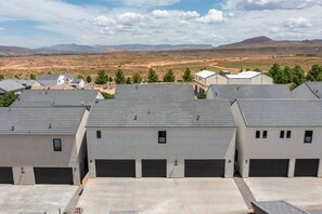 Zona residencial con casas modernas y garajes, con diseño de techo plano y vistas despejadas a montañas distantes.