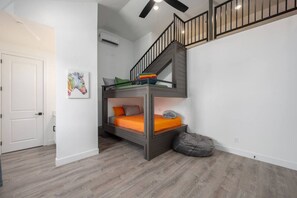 Habitación con literas, una escalera, una puerta y aire acondicionado instalado en la pared.