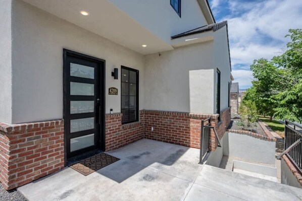 A building with a brick base and a white upper section, a black door, and a small window.