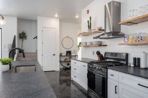 A modern kitchen with white cabinetry, a stainless steel range hood, and a built-in oven.