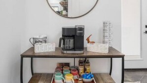 Una estación de café con una cafetera, una bandeja de tazas y una variedad de cápsulas de café.