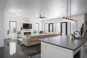 Une cuisine moderne dotée d’un îlot central, d’un four encastré et d’un ventilateur de plafond.