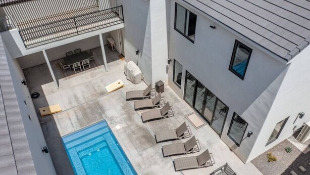 Un edificio moderno con piscina en la azotea, asientos exteriores y un patio cubierto.