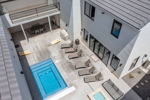 A modern building with a rooftop pool, outdoor seating, and a covered patio area.