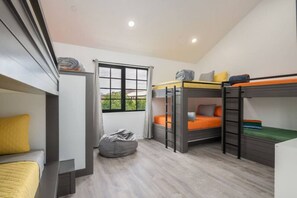 A compact room with bunk beds, a desk, and a bean bag chair.