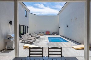 A rooftop pool area with lounge chairs, a barbecue grill, and a small pool.