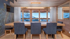 A wooden dining table with four chairs, large windows with a mountain view, and a wooden ceiling. - Stunning 4-room duplex for 10 in Avoriaz with ski-in/ski-out access (Avoriaz)