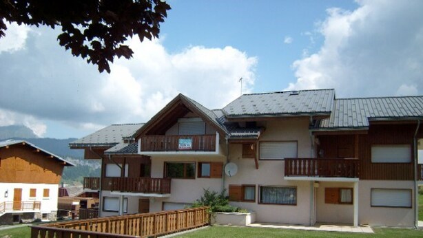 A multi-story hotel with balconies, a grassy lawn, and a mountainous backdrop. - Ski-in/Ski-out Apartment, 2 Bedrooms, Sleeps 4, Balcony, Parking, Crest-Voland (Crest-Voland)