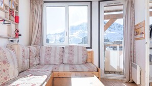 Ein gemütliches Zimmer mit einer Holzdirektiva, einem kleinen Tisch und einem Fenster mit Blick auf einen verschneiten Berg.