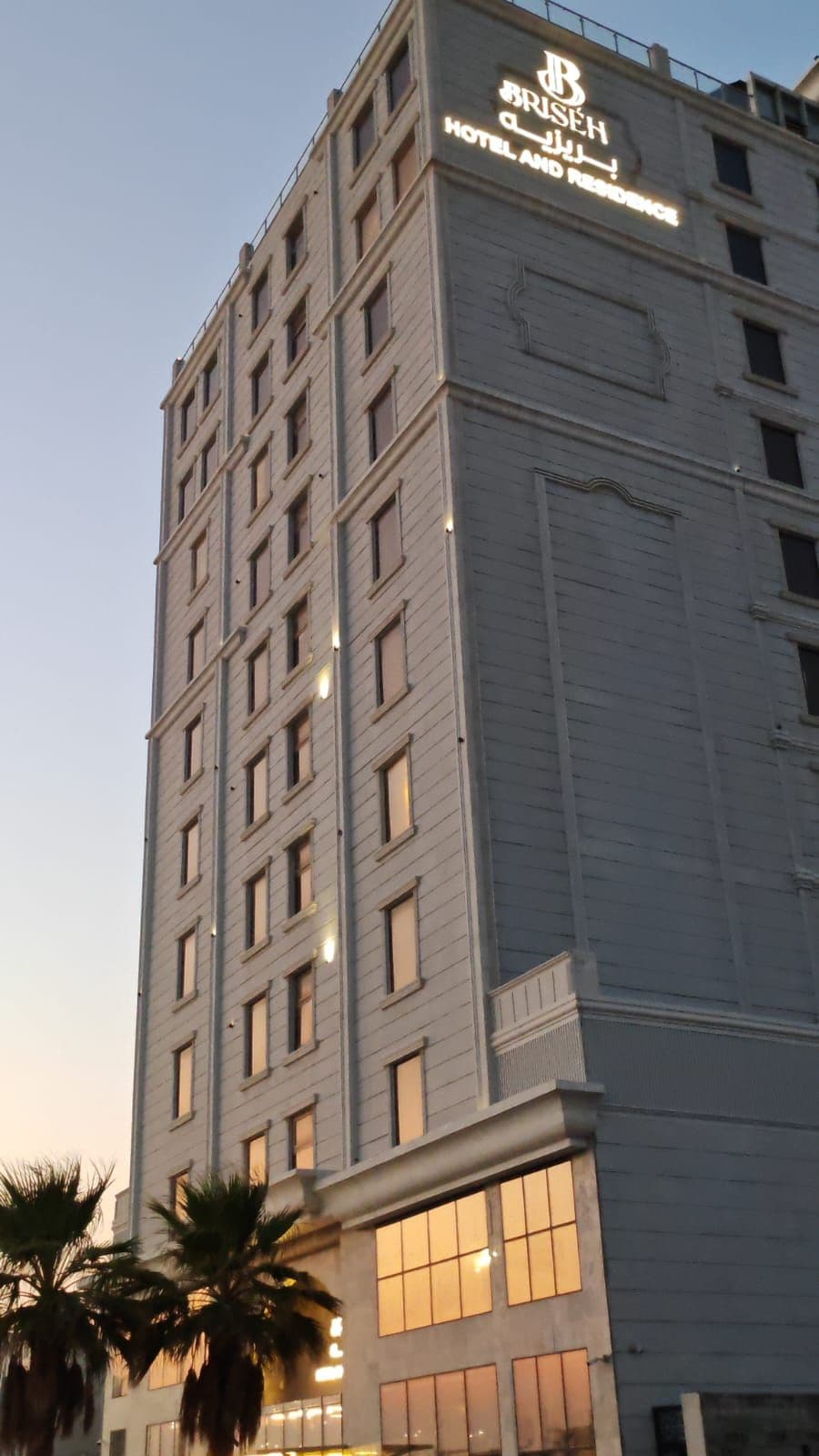 Un alto edificio alberghiero con diversi piani e finestre, con un cartello ben visibile in cima.