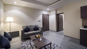 A modern living room with a sofa, coffee table, and lamp. - Enala AlKhobar Hotel (Al Khobar)