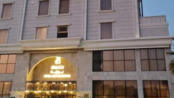 Un hotel de varios pisos con fachada moderna, amplios ventanales y una entrada destacada con señalización iluminada.