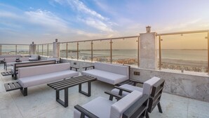 A rooftop terrace with seating and a view of the sea. - Briseh Hotel Alkhobar  (Al Khobar)