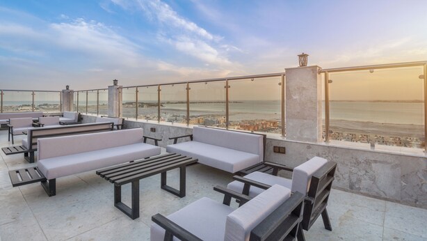 Una terraza en la azotea con mobiliario y vistas al mar.