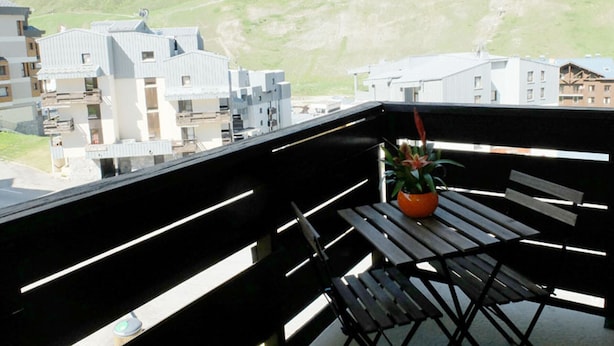 Un balcon avec vue sur une montagne et des bâtiments.