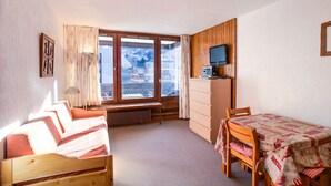 Une pièce confortable avec un lit, un bureau, une chaise et une fenêtre donnant sur des bâtiments et des montagnes.