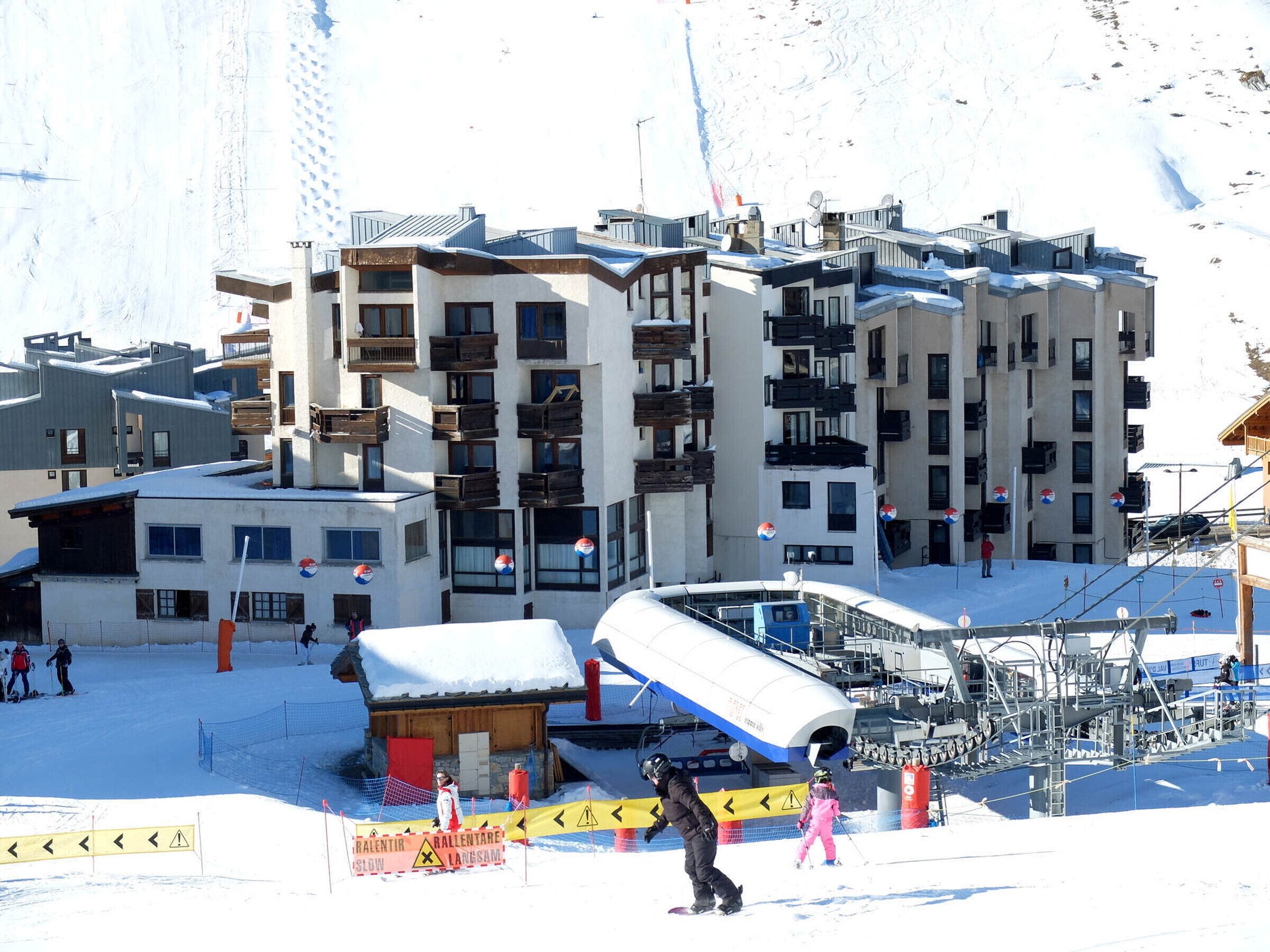 A ski resort with multiple buildings, including a hotel with balconies and a ski lift area.