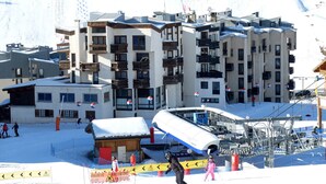 Une station de ski comprenant plusieurs bâtiments, dont un hôtel doté de balcons et une zone desservie par des remontées mécaniques.