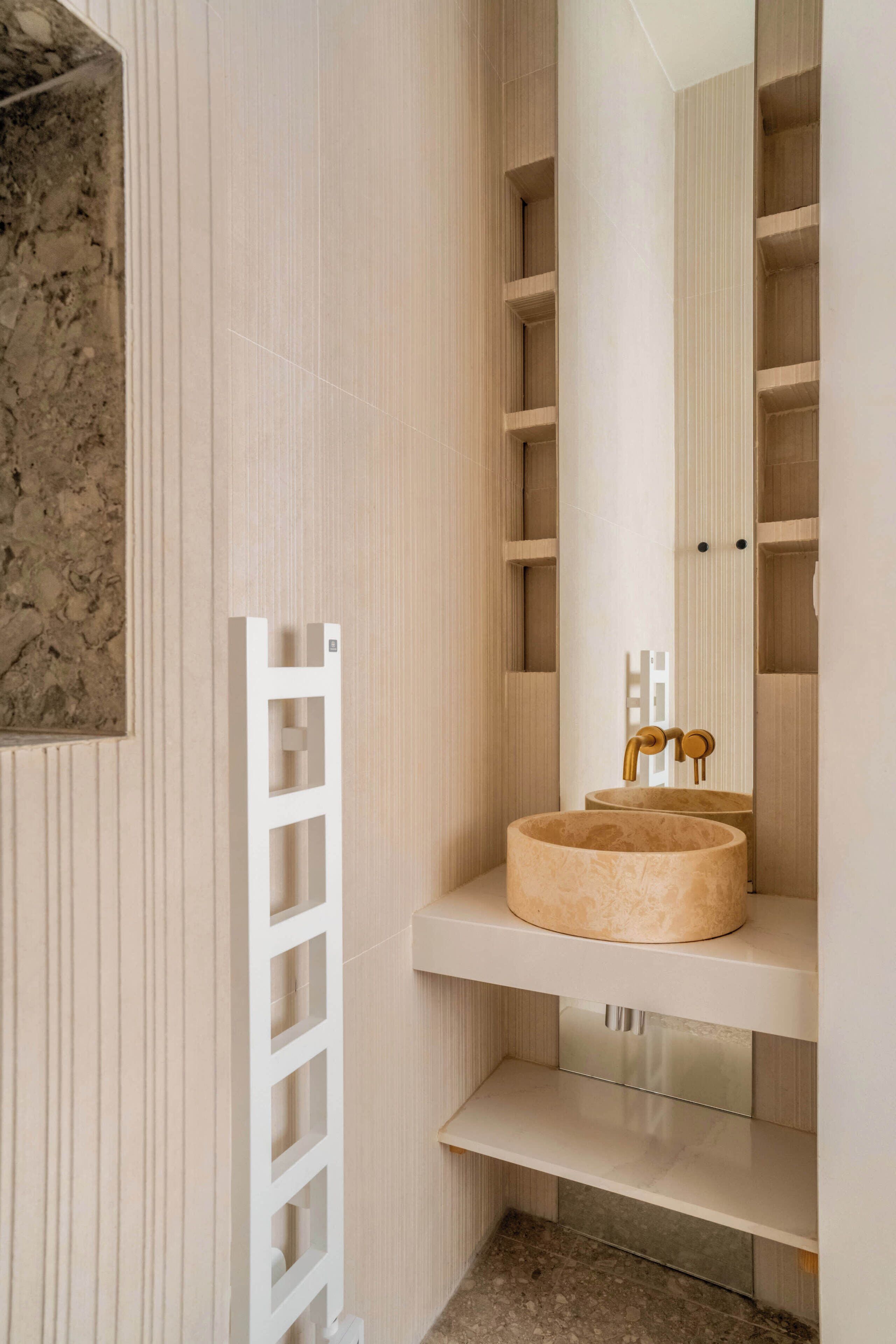 A bathroom with a round sink, a mirror, and a towel rack.